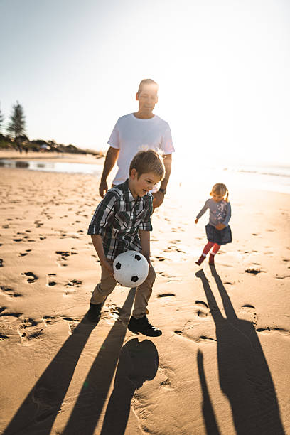 istock dad and son playing soccer on the beach 2227245149