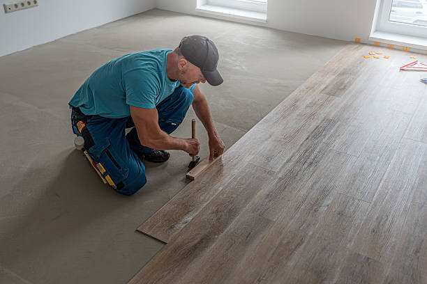 istock Floating floor work. The worker's hands taps the board of vinyl plank to lock the click system. He is using hammer and wooden plank. 2227256216