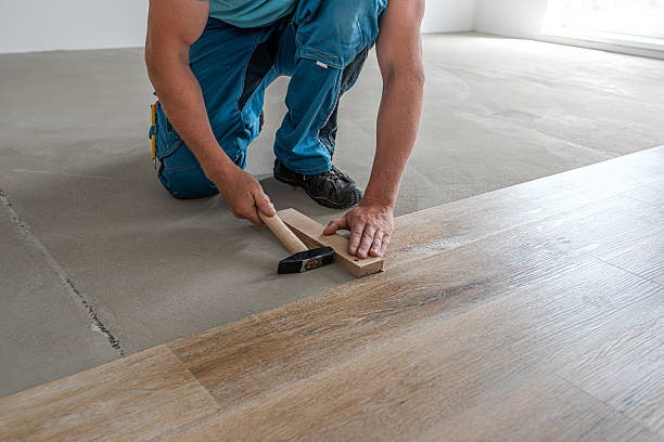 istock Floating floor work. The worker's hands taps the board of vinyl plank to lock the click system. He is using hammer and wooden plank. 2227256273