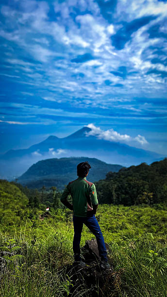 a man is standing looking at tomorrow on a savanna and mountain peak