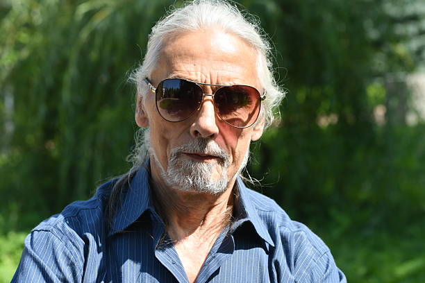 portrait of an elderly man with gray hair in a recreation park