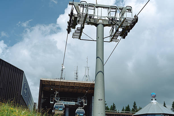 Wide view of a mid adult multiracial male tourist on vacation in Garmisch-Partenkirchen, Germany. He is walking into an overhead cable car at the top of the Zugspitze mountain with his friends, they are ready to see the view from the top.