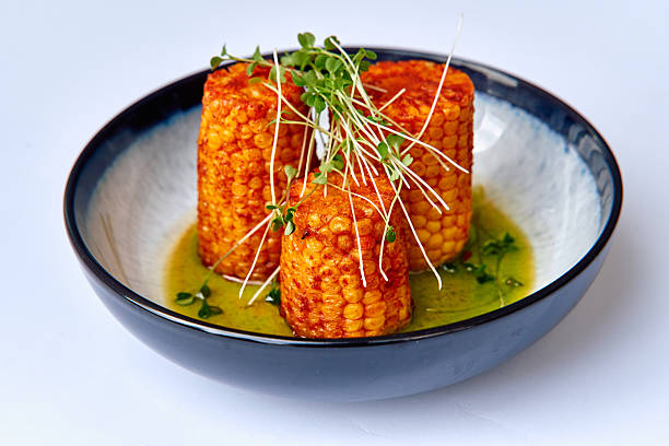 Deliciously Grilled Corn on the Cob with Vibrant Greens in a Flavorful Sauce Arrangement on a Stylish Plate