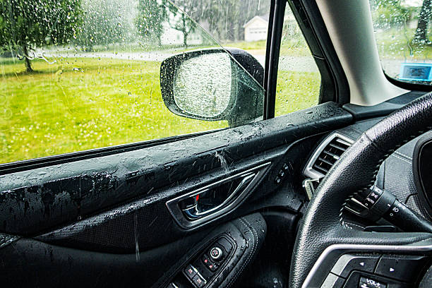 Car driver's side window being closed hurriedly during a sudden torrential rain storm downpour in a suburban residential district near Rochester, New York.