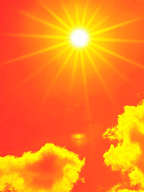 Bright sun with beautiful beams in the sky with some clouds. Toned in red color, space for copy.