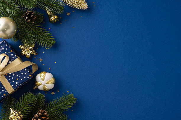 Festive flat lay composition featuring Christmas ornaments, a decorated gift, and pine branches on a vibrant blue background