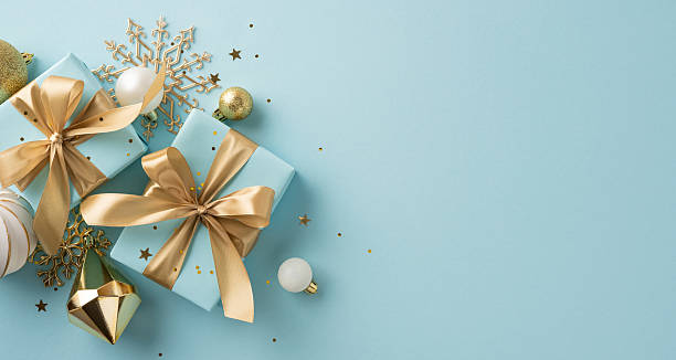 istock Beautifully wrapped presents with golden bows placed on a light blue background with decorations 2227284148