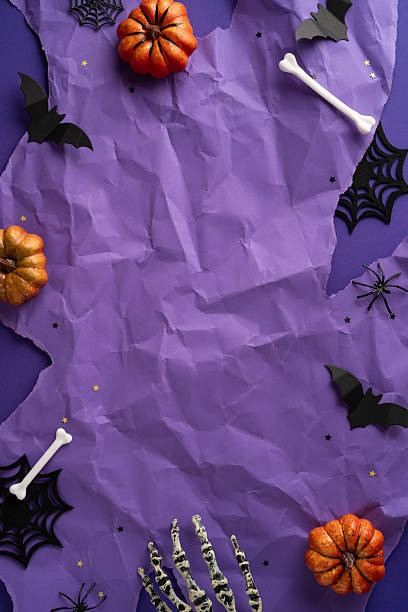 istock Purple vertical background with Halloween decorations including pumpkins, bats, bones, spider webs, and skeleton hands, creating a spooky seasonal atmosphere 2227284151