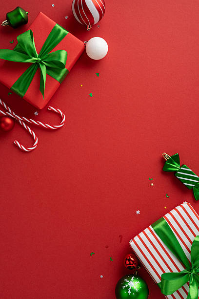 istock Top vertical view of Christmas presents and ornaments arranged creatively on a red backdrop 2227284155