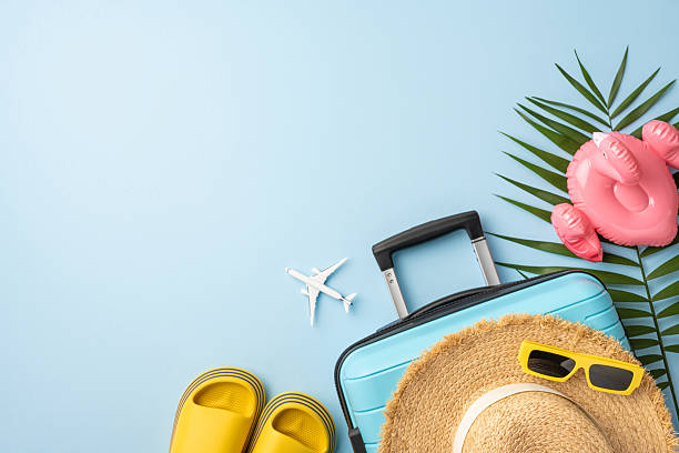 istock Flat lay image showcasing travel items including a suitcase, summer hat, and beach accessories on a light blue background 2227284176
