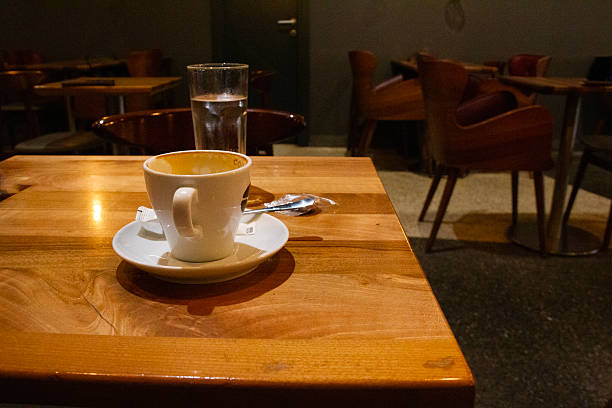 fresh espresso coffee with milk in a white cup on a tray with a small pot on the table