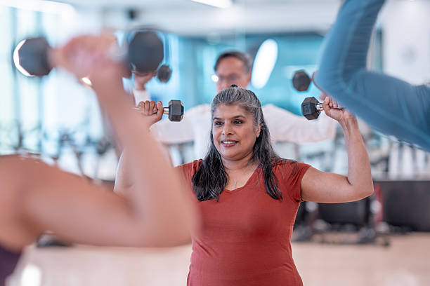 istock Group Fitness Class Participants Lifting Dumbbells in Modern Gym Setting 2227288190