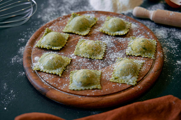 Aromatic Homemade Ravioli on a Wooden Board Dusting of Flour Highlighting Fresh Ingredients and Culinary Creativity in Italian Cuisine stock photo