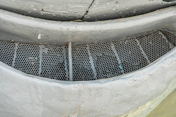 Image shows a timeworn concrete wall with an open metal grate on its side, inviting curiosity about what lies beyond No additional objects or text visible muted color palette of grey and industrial