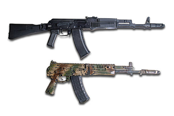 istock Side-by-side rifles on a plain background, one black AK-style matte finish, folding stock, pistol grip, vertical foregrip and the other camouflage design organic furniture, woodland colors Both 2227290586