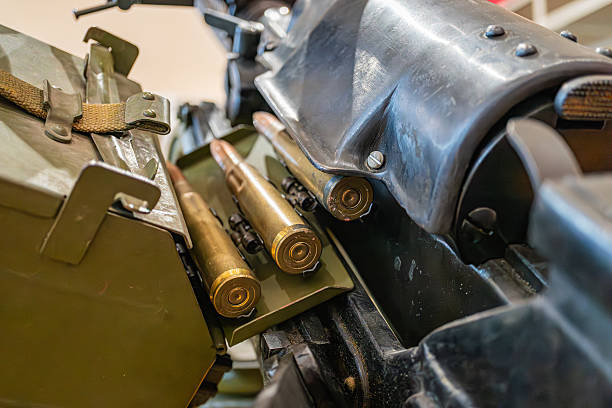 istock Image of a green storage container filled with metallic rifle rounds, along with additional military equipment like a black metal component Scene suggests readiness for assembly 2227292637
