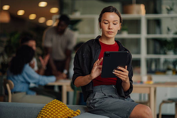 istock Young manager using digital tablet in startup office with team working in background 2227295500