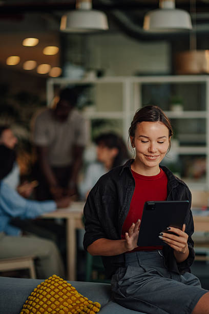 istock Young businesswoman using digital tablet in modern office with colleagues working in background 2227295501