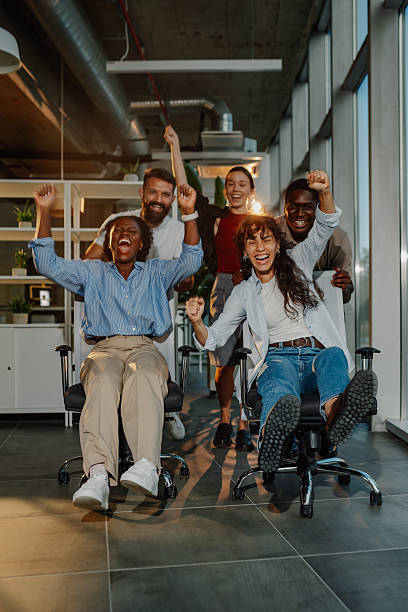 istock Excited business team celebrating success, having fun riding office chairs 2227295595
