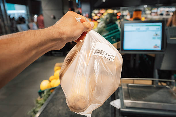 istock Hand holding a plastic bag with groceries and barcode sticker at a self checkout counter in a supermarket 2227298170