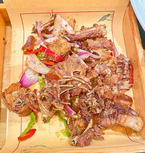 istock A rustic dish of deep-fried duck or chicken bones and scraps, mixed with red onion and chili, served in a wooden tray 2227303611