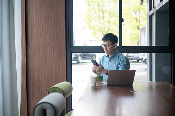 istock Businessman working on a laptop computer and texting or using social media on a mobile phone in the office 2227311062
