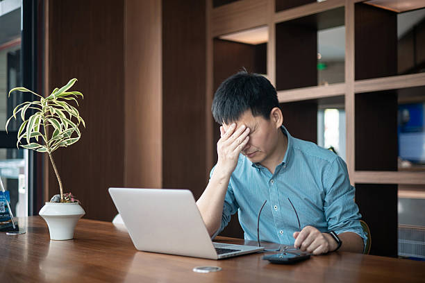 istock A tired Asian man rubbing his face in front of the computer 2227311171