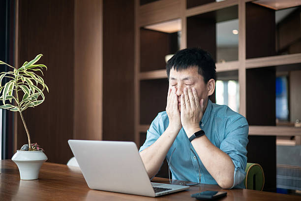 istock A tired Asian man rubbing his face in front of the computer 2227311173