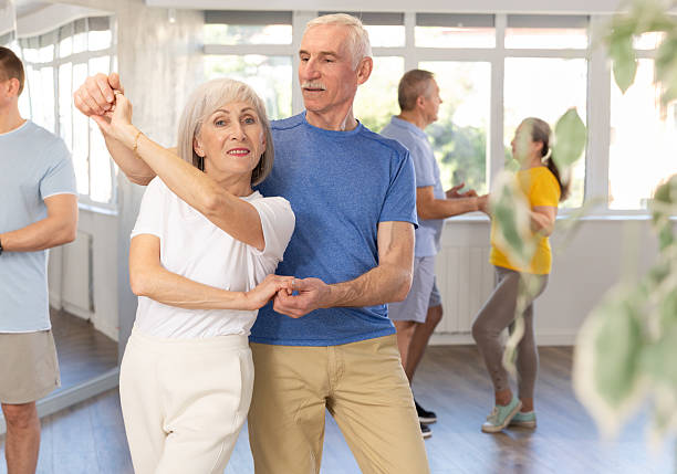 istock Group of elderly pensioners learn to dance a couple tango dance in dance class 2227317047
