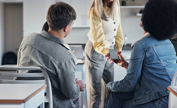 Phone, confiscation and teacher with students in classroom for rules, discipline or technology ban. Education, school and educator with children for distraction take away in lesson at academy.