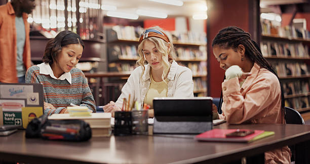 istock Education, college and friends with women in library for assignment, reading and study group. University, learning and teamwork with people on campus for knowledge, students and research project 2227322942