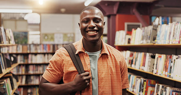istock African man, student and smile at library, portrait or excited for education, development or research at college. Person, happy and learning with pride, backpack or scholarship at university 2227322984