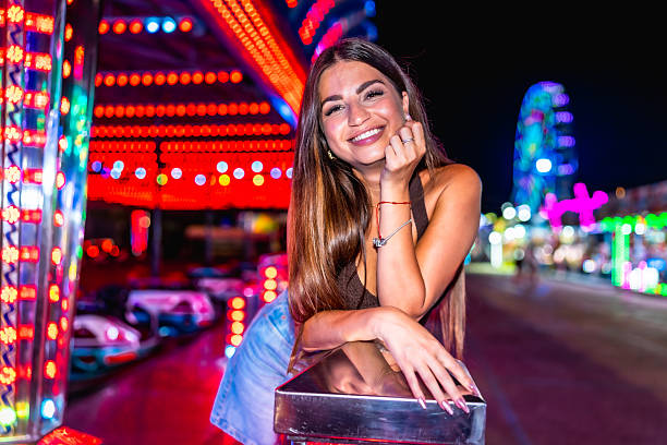istock Young woman smiling at amusement park at night 2227323723