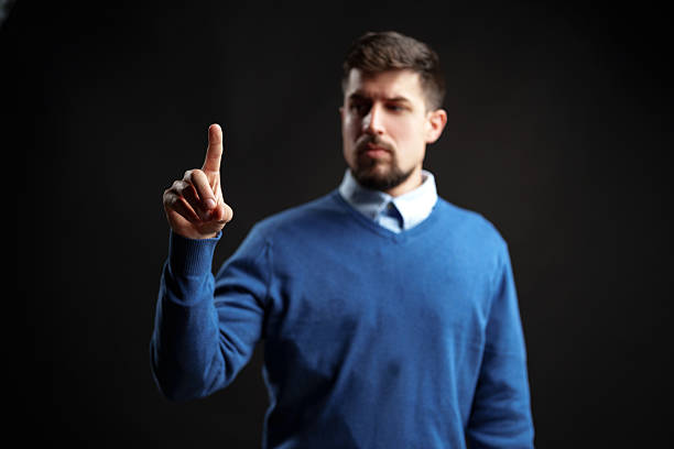 istock Engaging man gestures with one finger to convey a message in a dark studio setting 2227327697