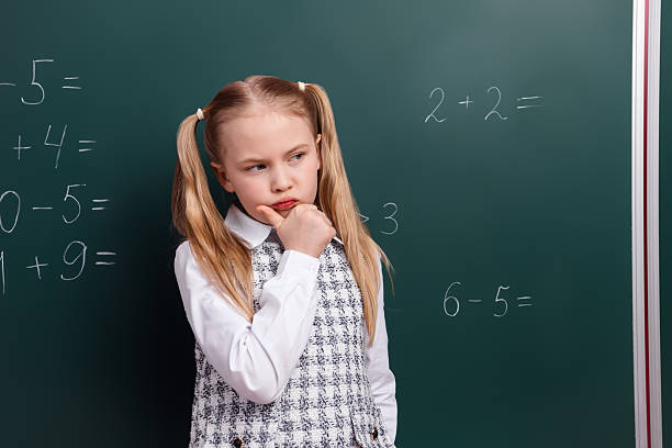 istock Thoughtful schoolgirl in uniform reflects on math problems written on a chalkboard during a classroom lesson 2227329148