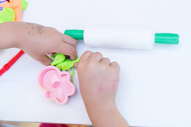 istock child molding a green polymer clay doll on a white background 2227334523
