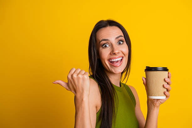 istock Charming brunette smiling while holding coffee cup against bright yellow background exuding style lifestyle and positivity 2227335106