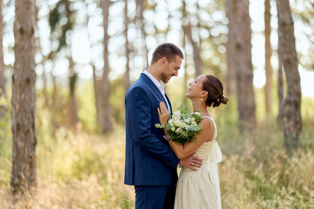 Wedding couple walking between trees in forest.