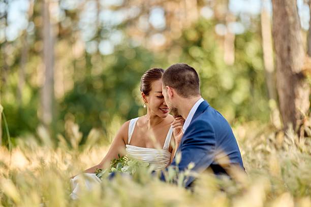 istock Romantic Newlywed Couple Sitting Outdoors on Their Wedding Day in a Natural Setting 2227337031