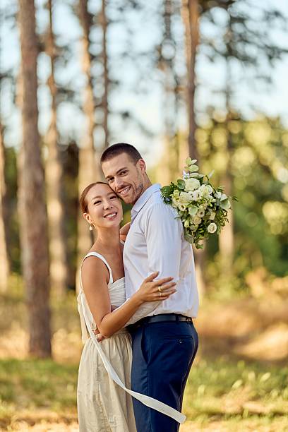 istock Smiling Couple Embracing Outdoors During Wedding with Floral Bouquet 2227337054