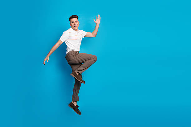 istock Young man posing joyfully in a casual outfit against a bright blue background, expressing happiness and energetic positivity 2227337099