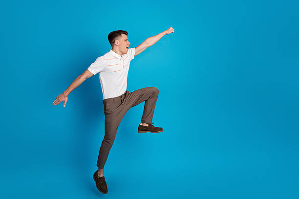 istock Young man posing dynamically with vibrant blue background, showcasing stylish and confident fashion with creative energy 2227337100