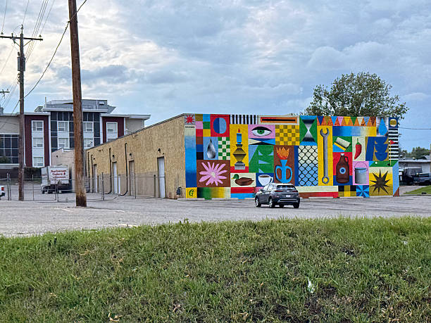 Calgary, Alberta, Canada. Jul 27, 2025. A vibrant mural transforms a Calgary building, showcasing an eclectic mix of abstract and symbolic elements under a cloudy sky, celebrating urban art.
