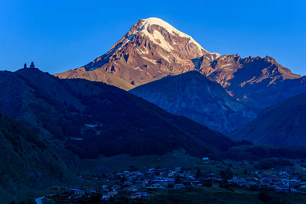 The Gergeti Trinity Church (Tsminda Sameba) is a Georgian Orthodox church built in the 14th century, with Mount Kazbek, a stratovolcano in the Caucasus Mountains, towering behind the church.
