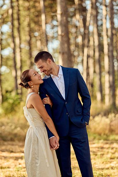 istock Romantic Couple Embracing in Sunlit Forest with Elegant Attire 2227339874