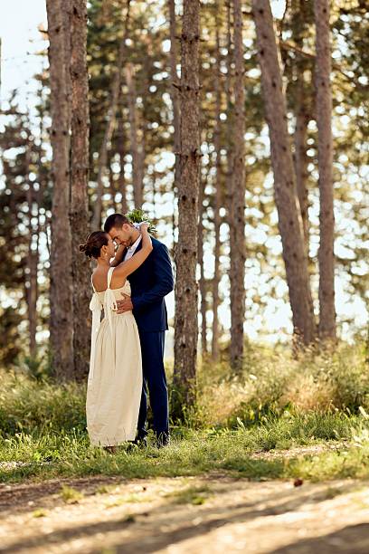 Romantic Newlyweds Embracing in a Sunlit Forest During Their Wedding Day