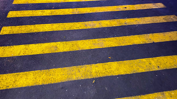 istock This image shows a zebra crossing on asphalt, featuring bold yellow stripes against a dark road surface, indicating a pedestrian crossing area. 2227344704