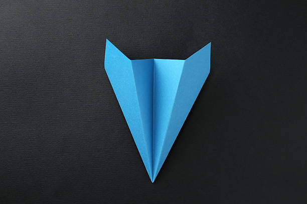 istock One handmade light blue paper plane on black background, top view 2227347555