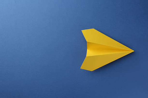istock One handmade yellow paper plane on blue background, top view. Space for text 2227347558
