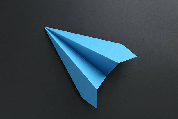 istock One handmade light blue paper plane on black background, top view 2227347578
